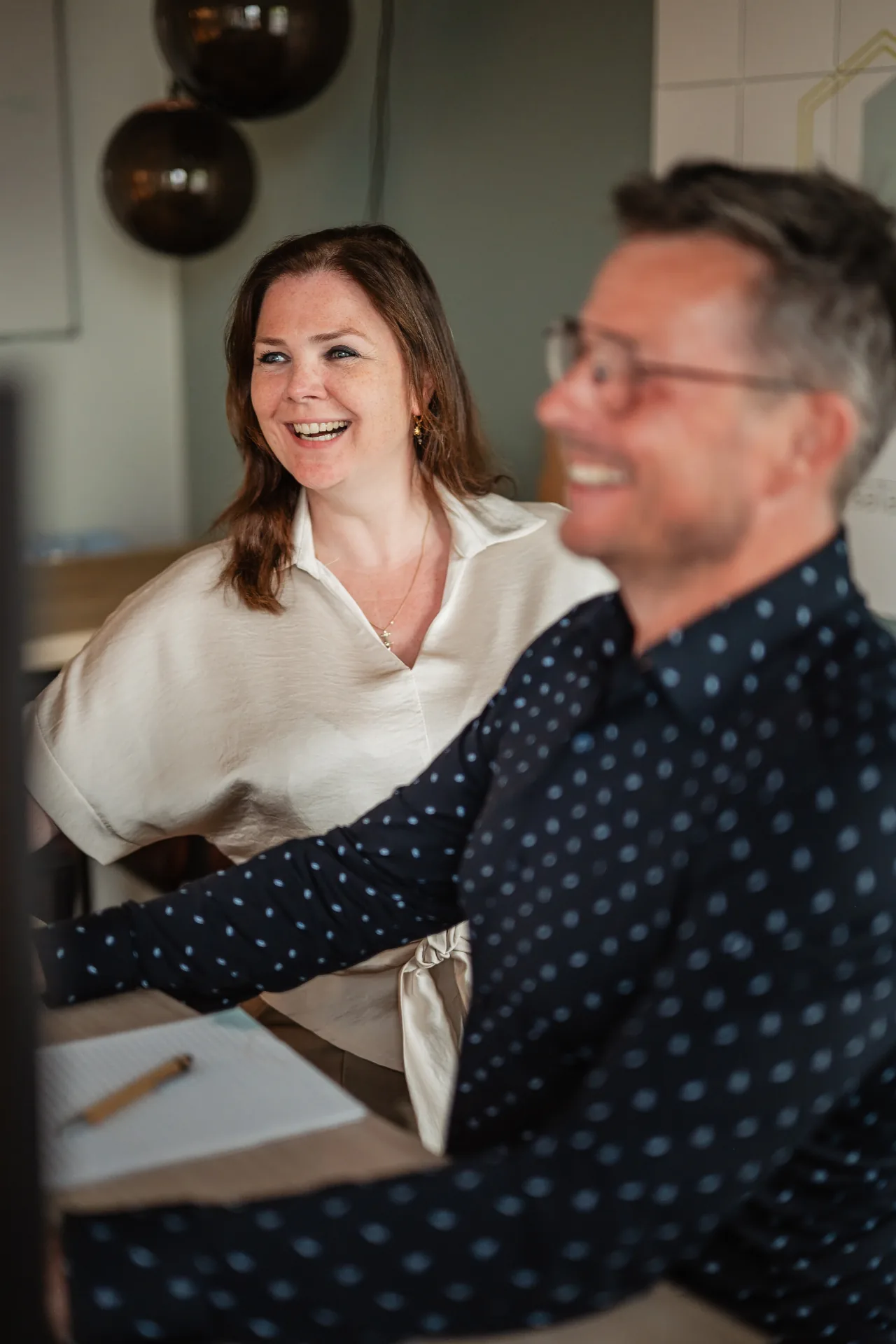 Collega's van PoortEijk lachend in overleg aan tafel