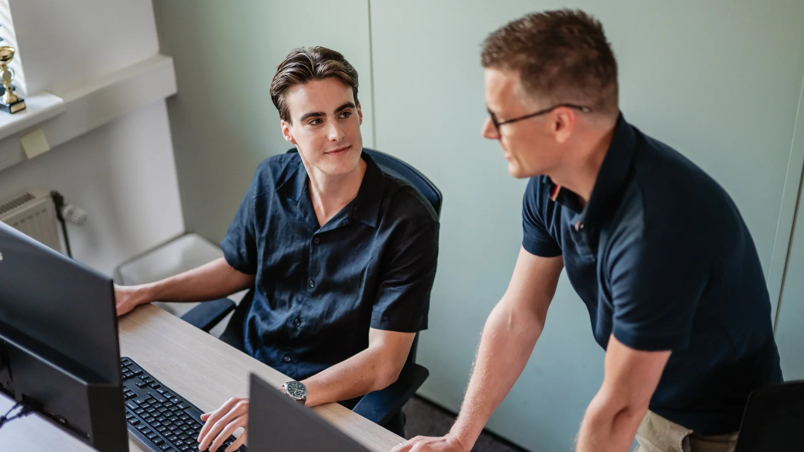 Twee adviseurs van PoortEijk bespreken werk aan een bureau